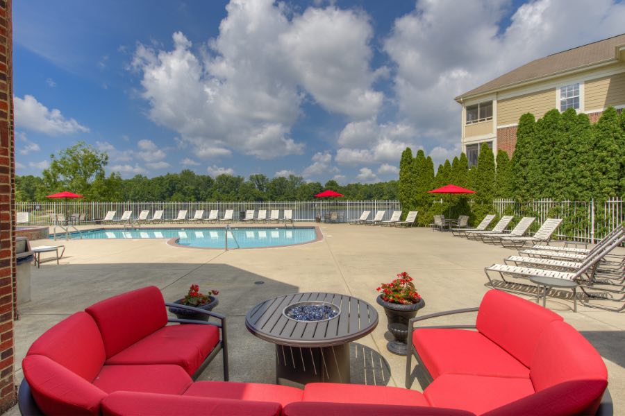 A swimming pool like this one at North Haven Apartments is a great place to meet people. Apartment swimming pool area with cushioned red seating